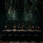 Chic dining setup with candles and hanging plants, exuding a cozy ambiance.