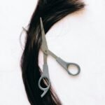 A pair of scissors and cut hair on white background, perfect for salon or haircut concept.
